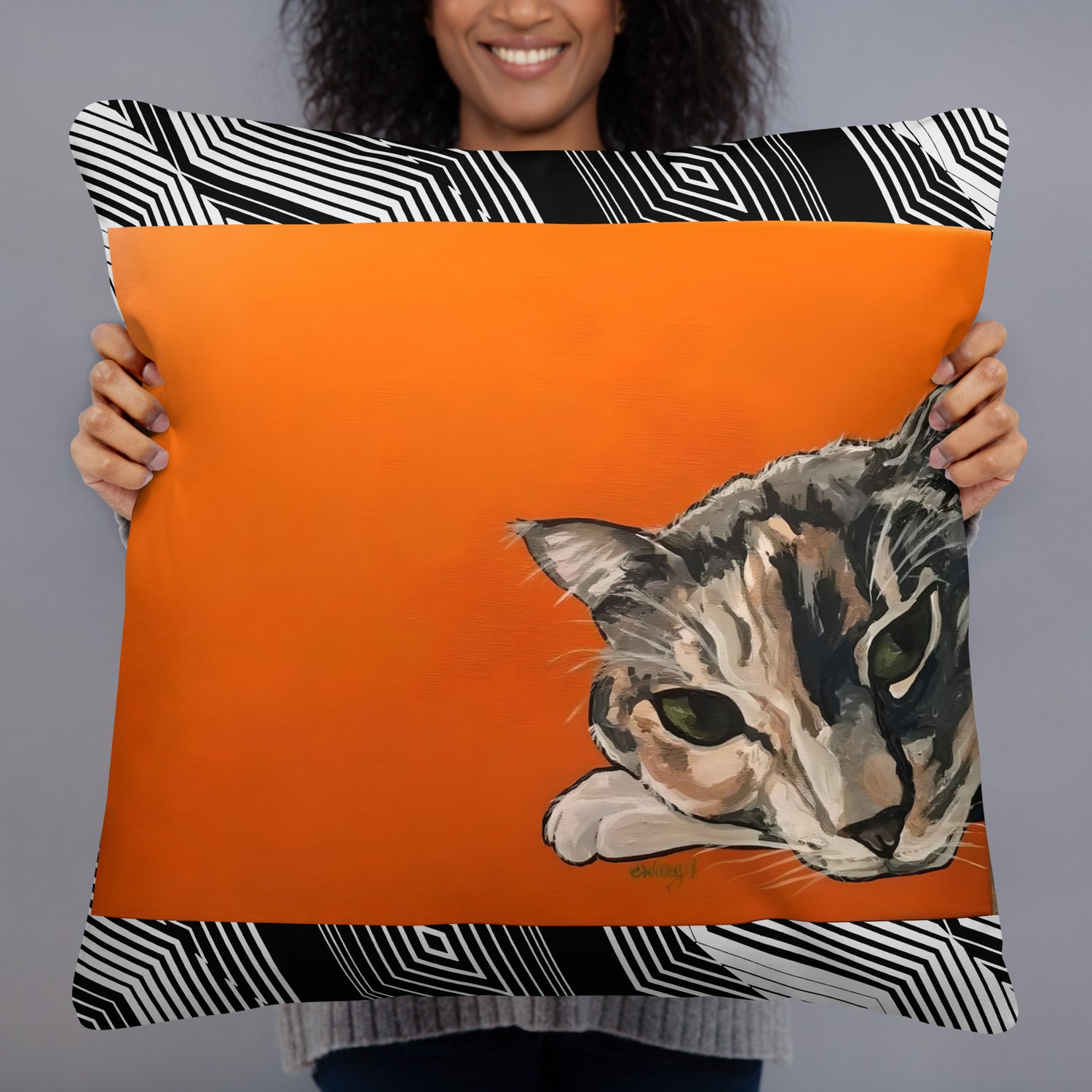 woman holding a throw pillow with a calico cat on an orange background