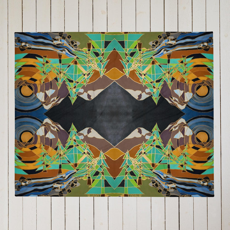 A throw blanket on a wooden floor with abstract pine trees, mountains, a river and a sun out lined in metallic gold.
