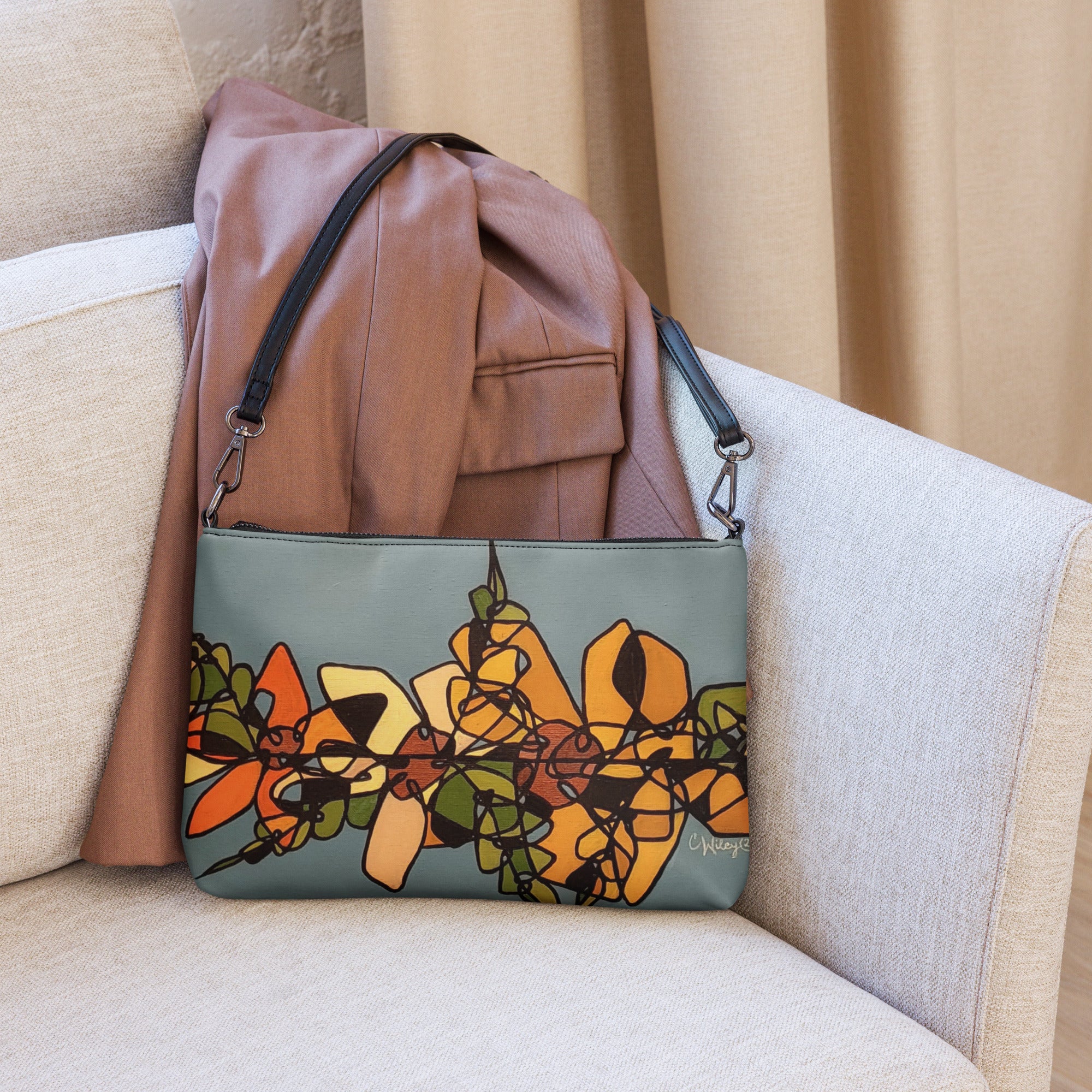 A purse with a black strap in blue with abstract orange and black flowers